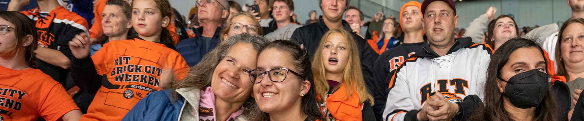 A student and her mother appear in a crowd of people at an RIT hockey event