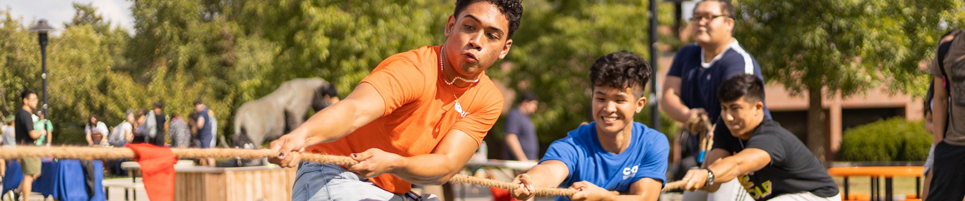 Three students pulling on a rope playing tug-of-war at the annual MudTug event