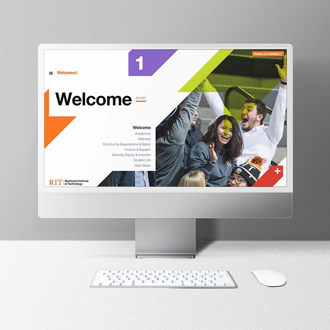 Silver desktop computer shown on a white table with a grey background. On the computer screen is the Virtual Orientation platform.