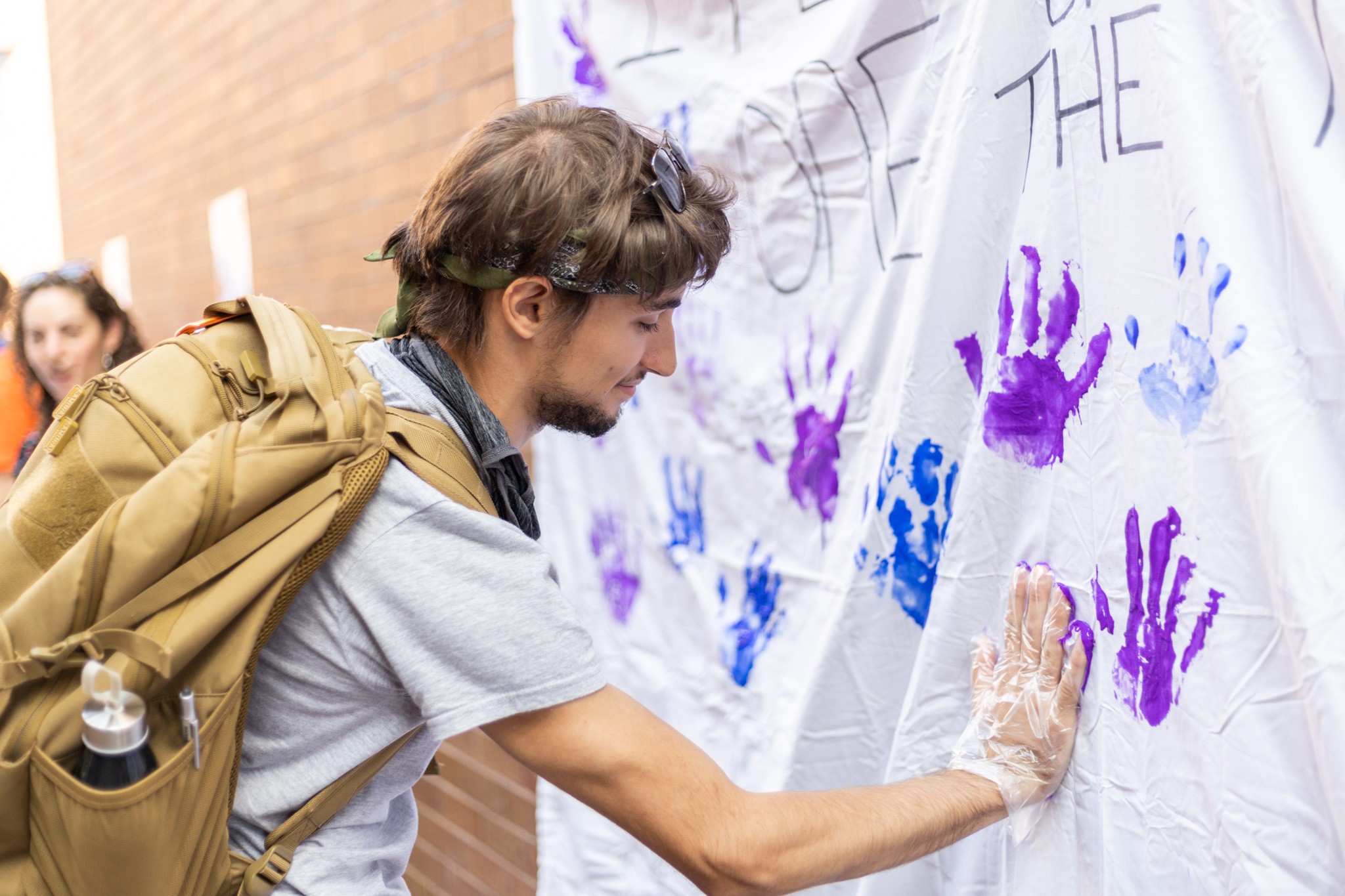 Student with paint on hand leaving a hand print on an NSPW art installation