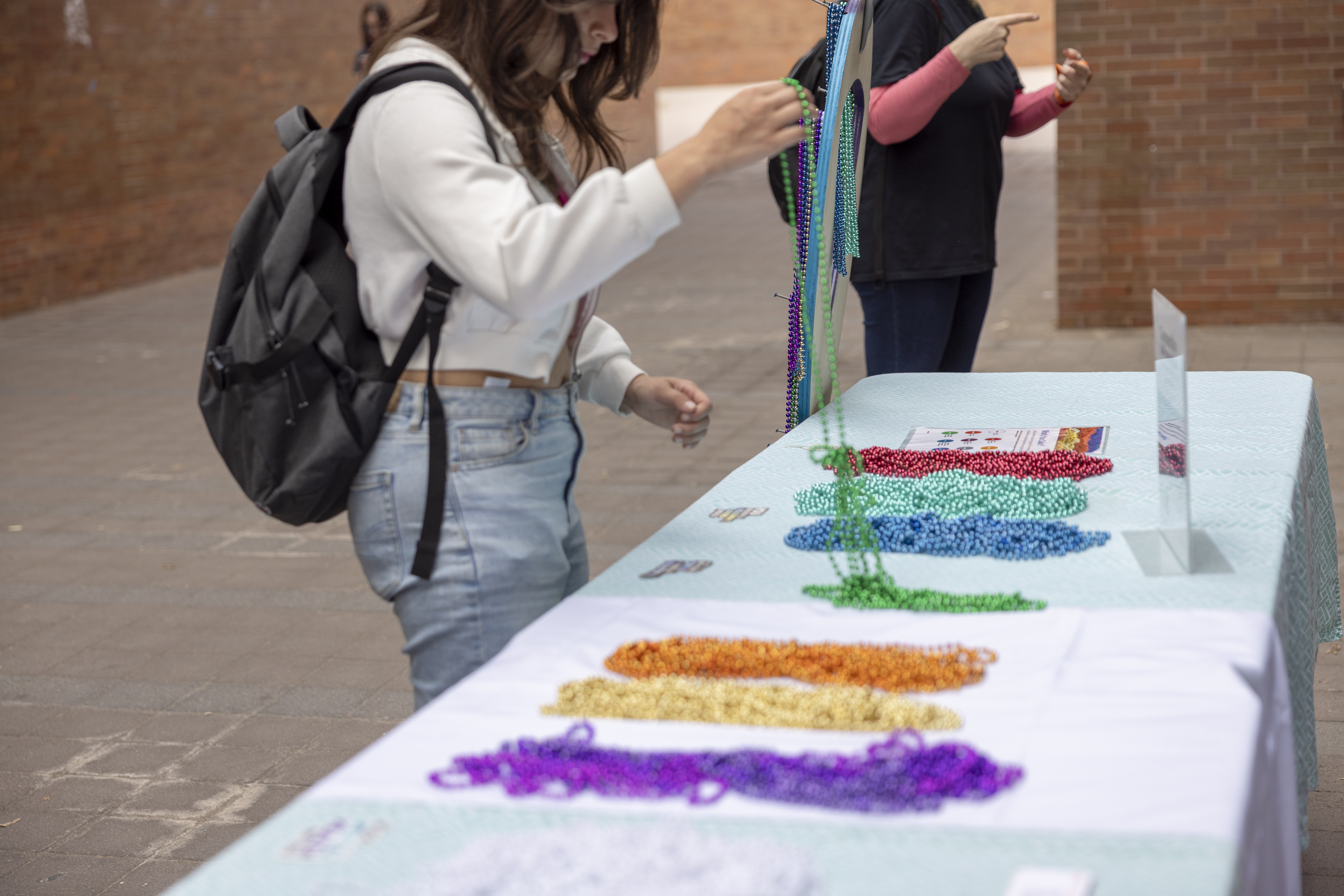 Student with at an NSPW table picking up honor colorful honor beads