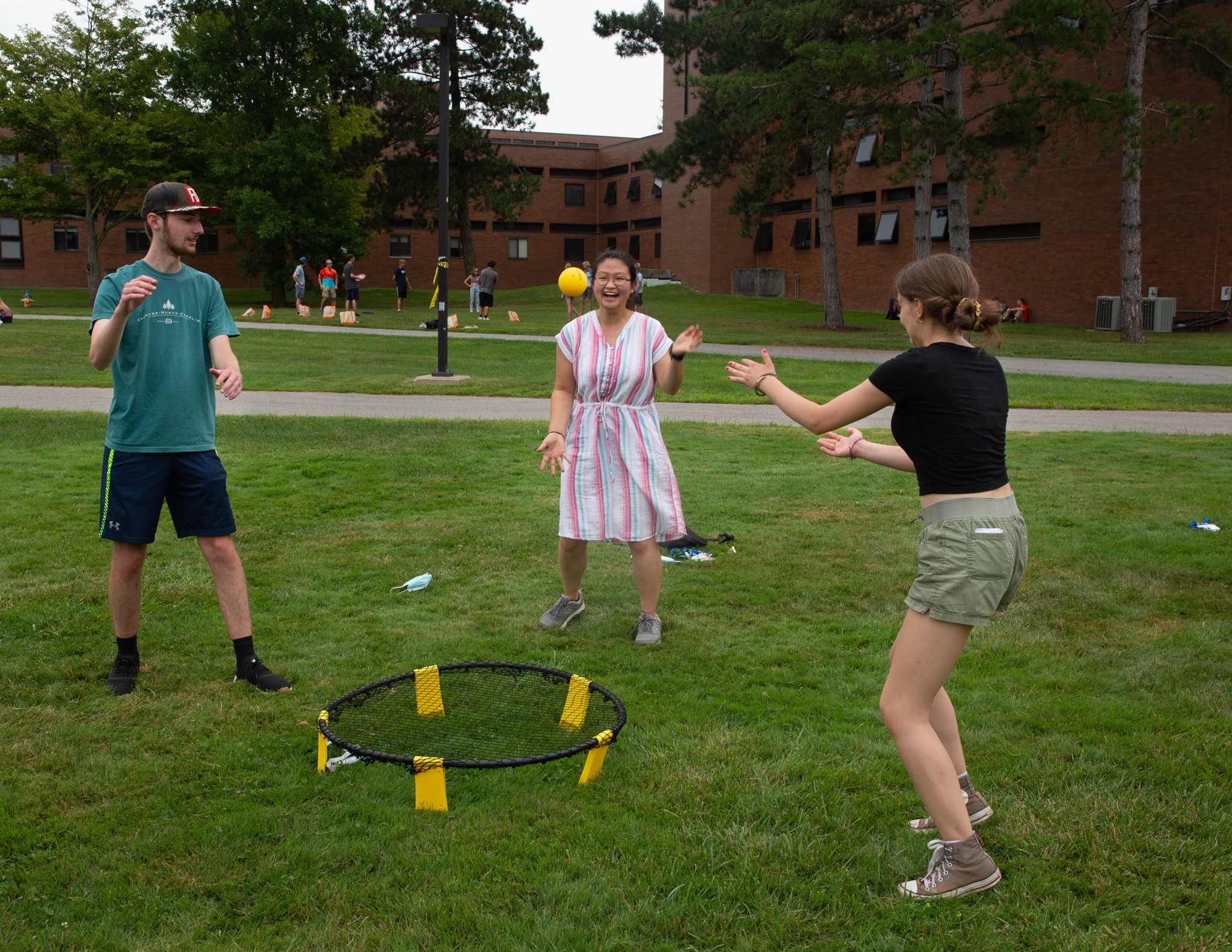 Students outside in a circle playing spikeball