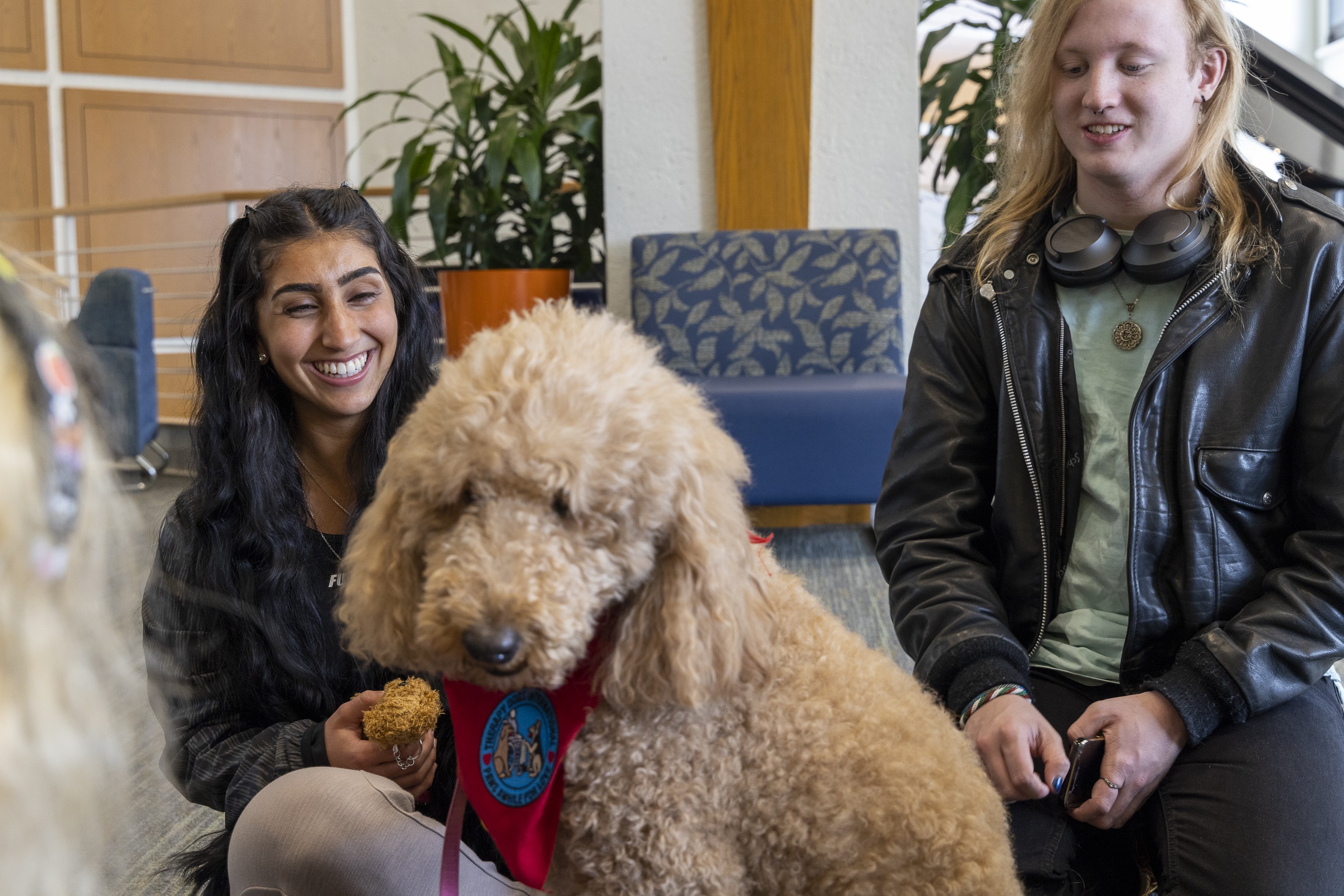 Two students smiling at Bow Wow Wellness petting a therapy dog