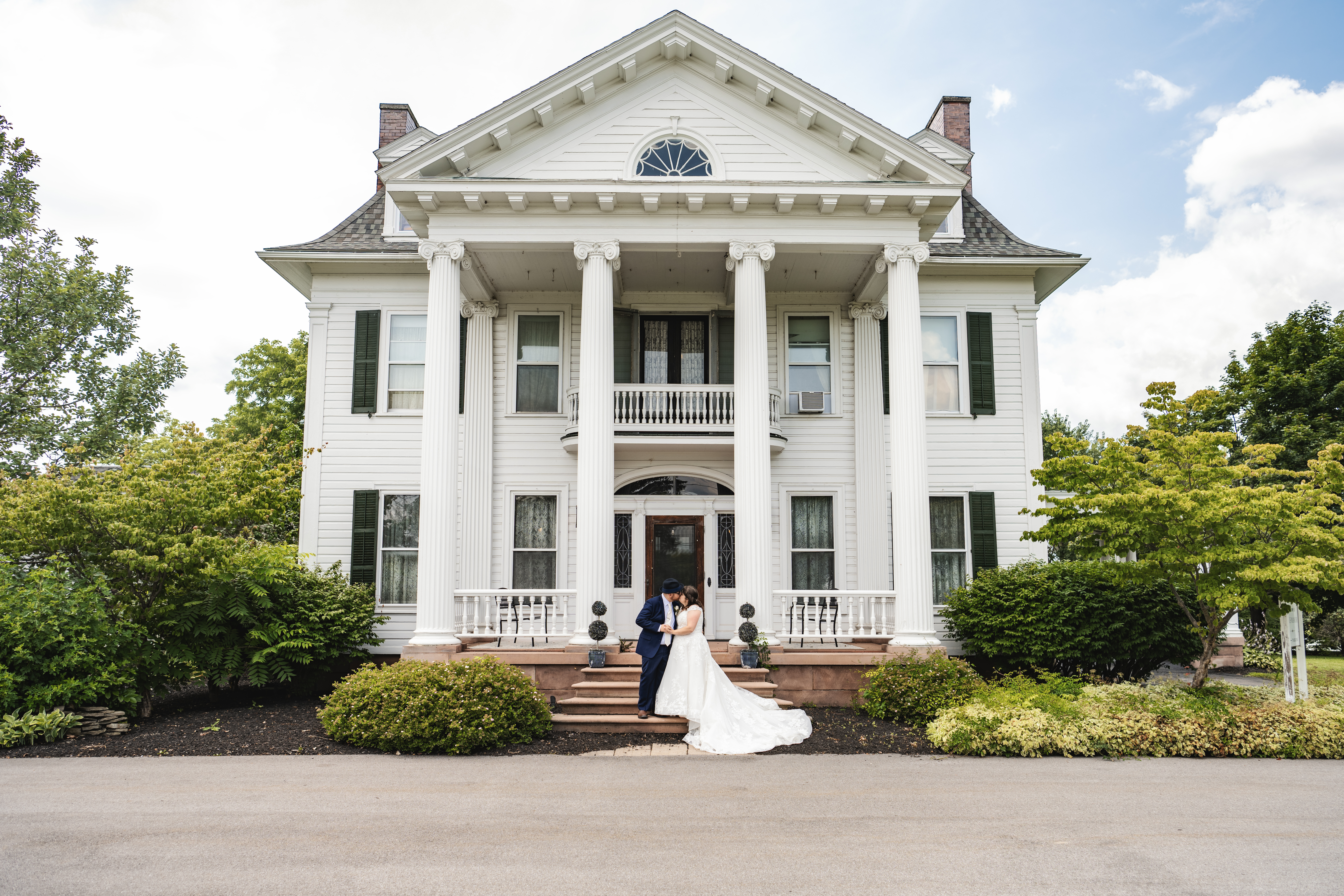 Josh and Julia Haber, wedding photo of them standing outside of a large white house venue