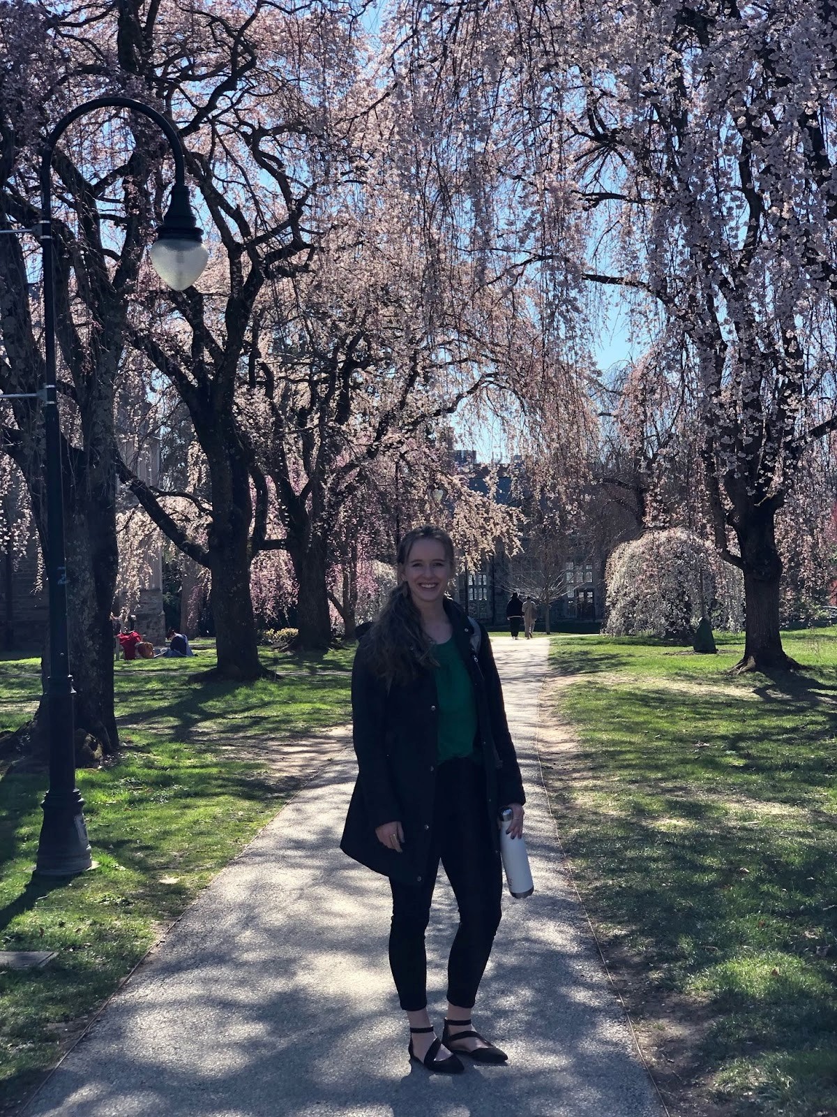 Arianna Giguere  stands in front of flowering trees on the Bryn Mawr campus.
