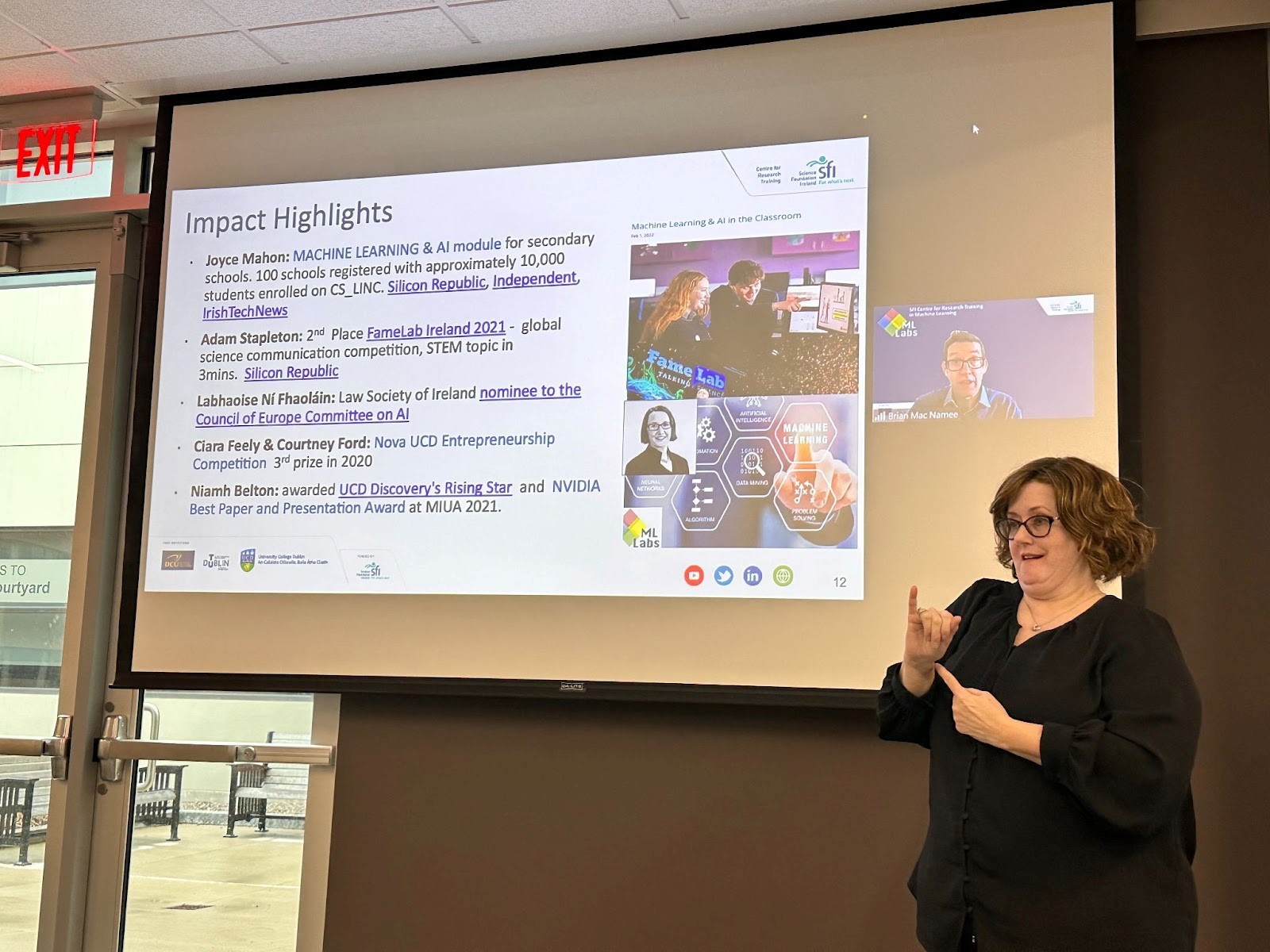 An ASL interpreter stands in front of a screen that shows a presenter (Brian Mac Namee) and their slide. The title of the slide shown says "Impact Highlights".