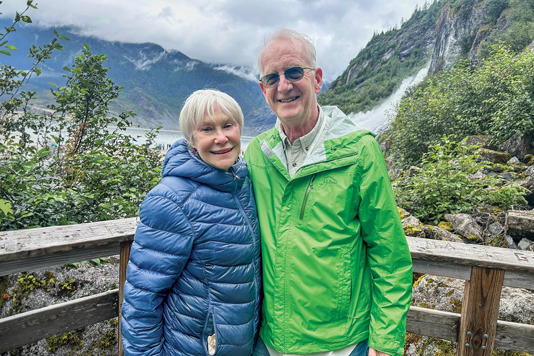 Sue (Mozzer) Mather BS '74 and Bob Mather BS '74 take a picture outdoors in front of a waterfall