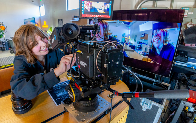 Person operating a professional video camera in a studio setting.