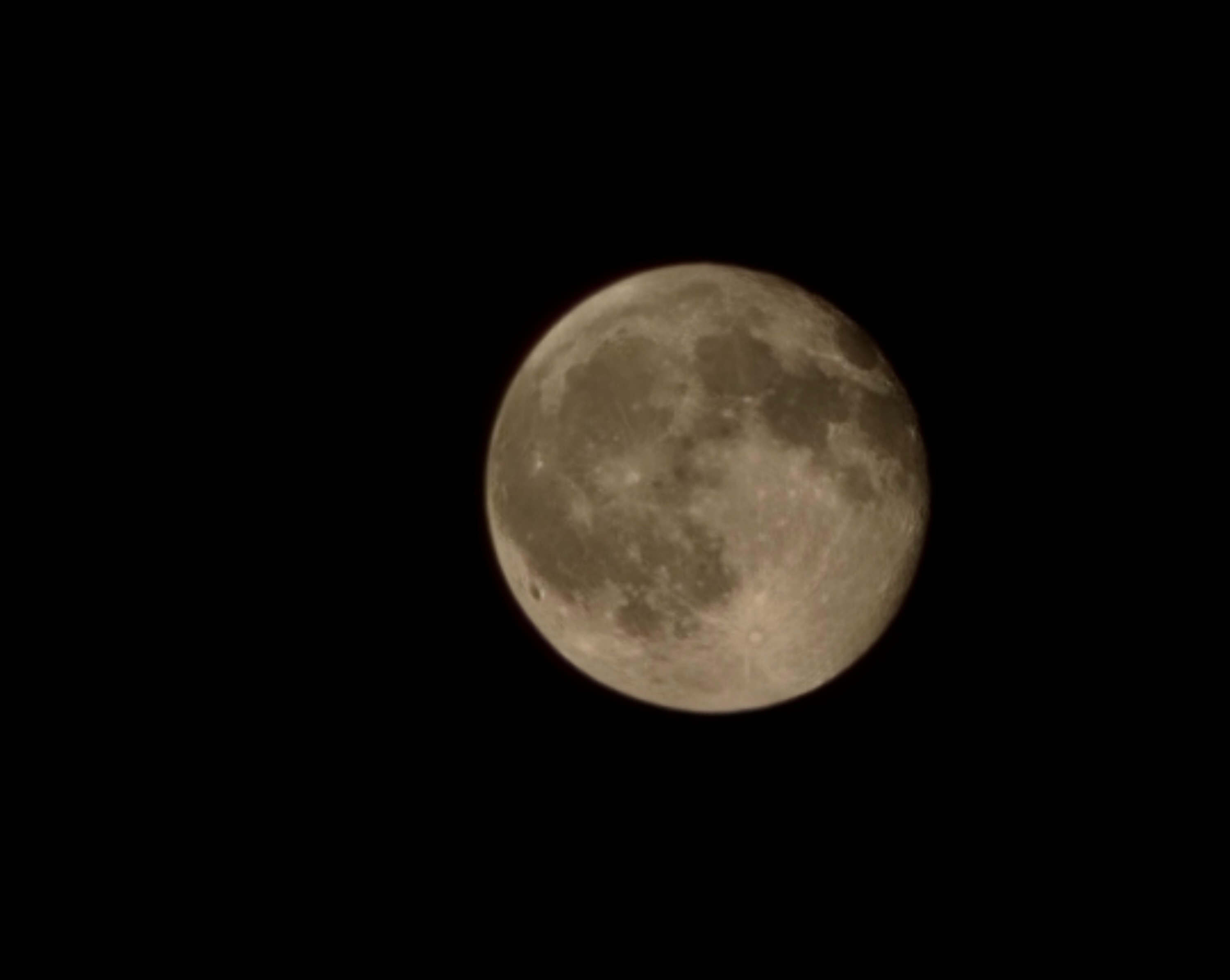 Close-up of the orange-tinted moon against a black sky.