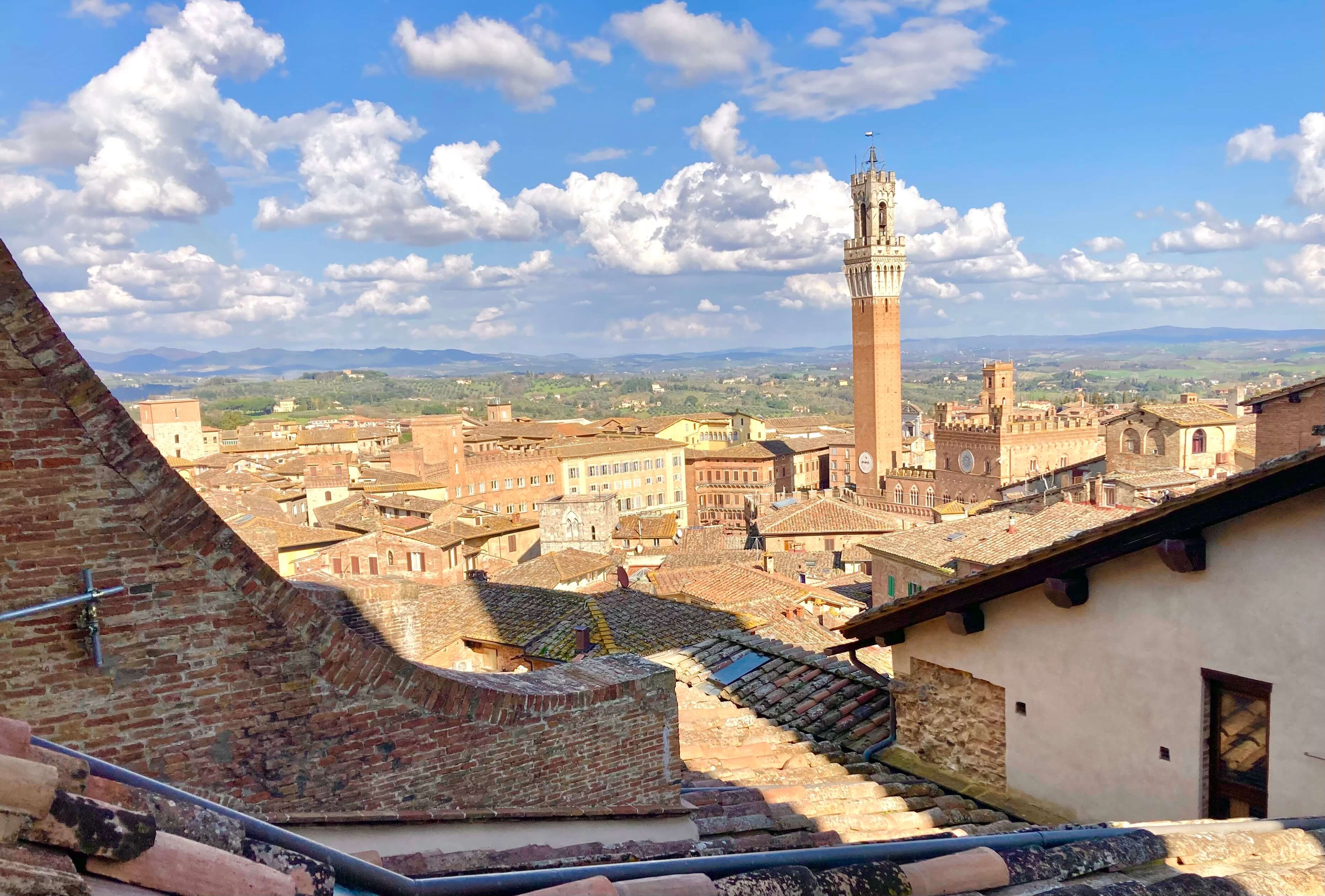 Sunlit medieval brick buildings in Siena, Italy.