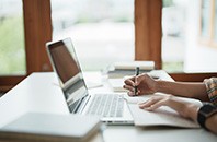 Young woman student busy study make notes in notebook and using laptop concentrated online training course technology education.