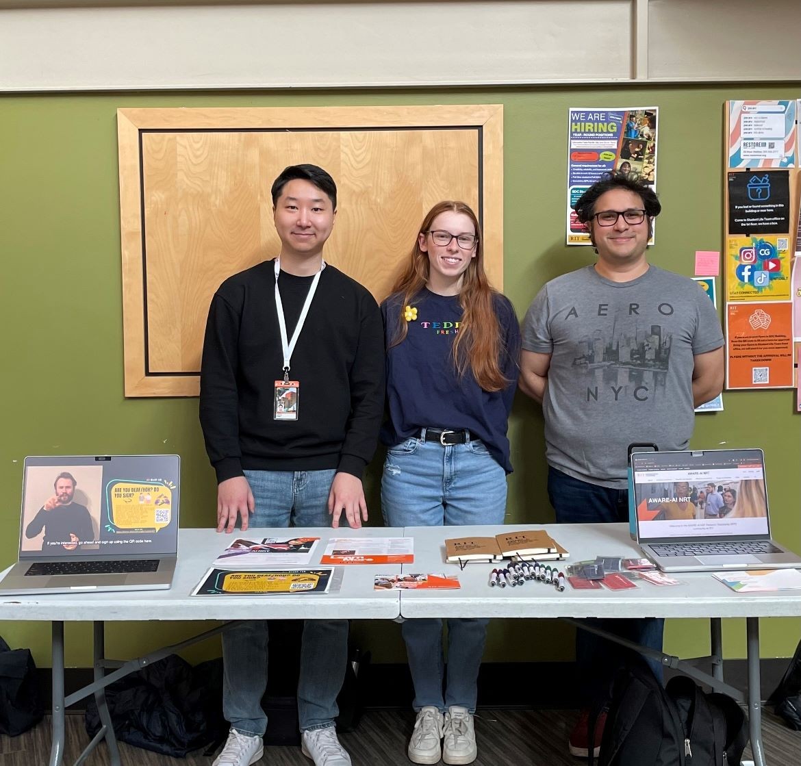 Gabriel Park, Shannon Regelsberger, and Michael Peechatt standing at an informational table about the AWARE-AI Program
