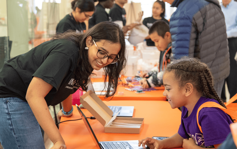 Graduate Senator engaging with a girl at an interactive table during an event.