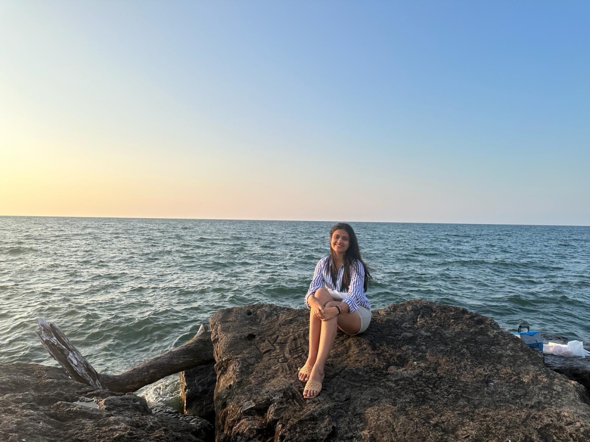 Khushi sitting on a rock by the waters‌