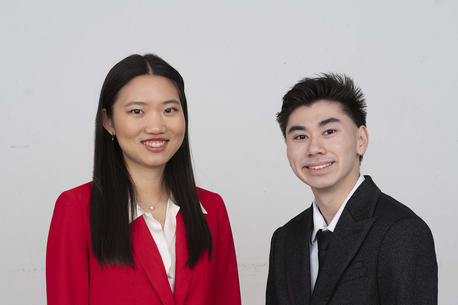 Two professionally dressed students smiling and posing for a formal portrait against a plain background.