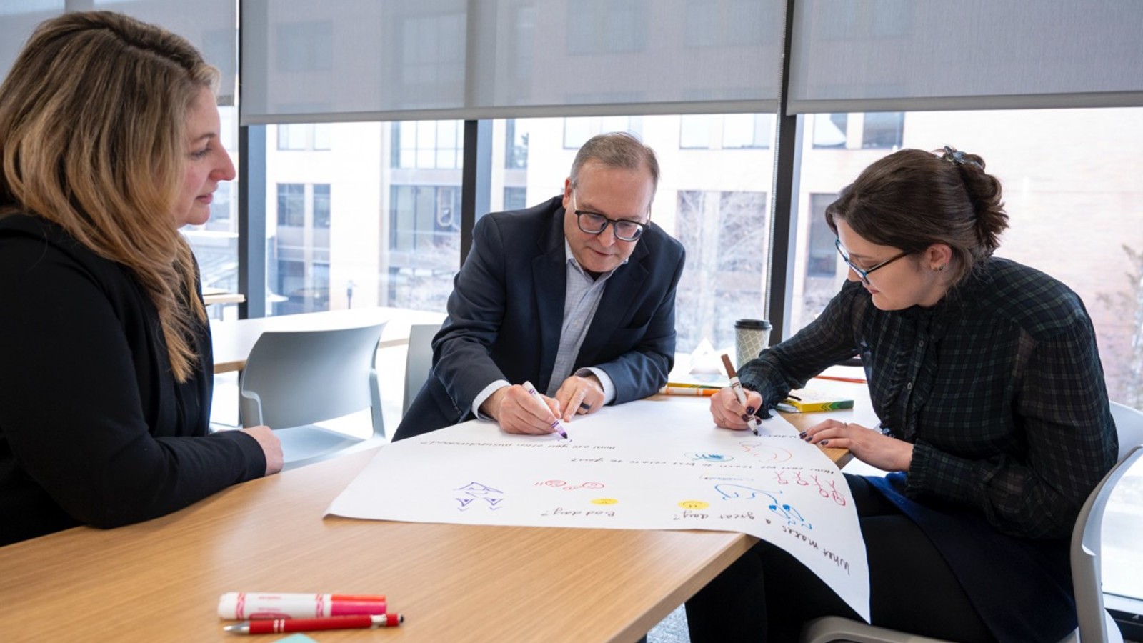 Executive MBA Students working together with markers in hand