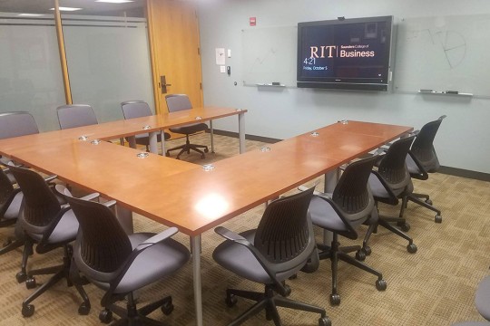 Conference Room with U shaped table surrounded by chairs.
