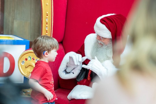 Charles Graves, portraying Santa Claus, uses sign language to communicate with a deaf child.