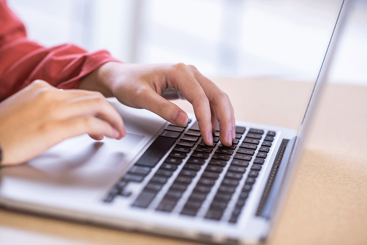 A close up of two hands typing on a laptop.