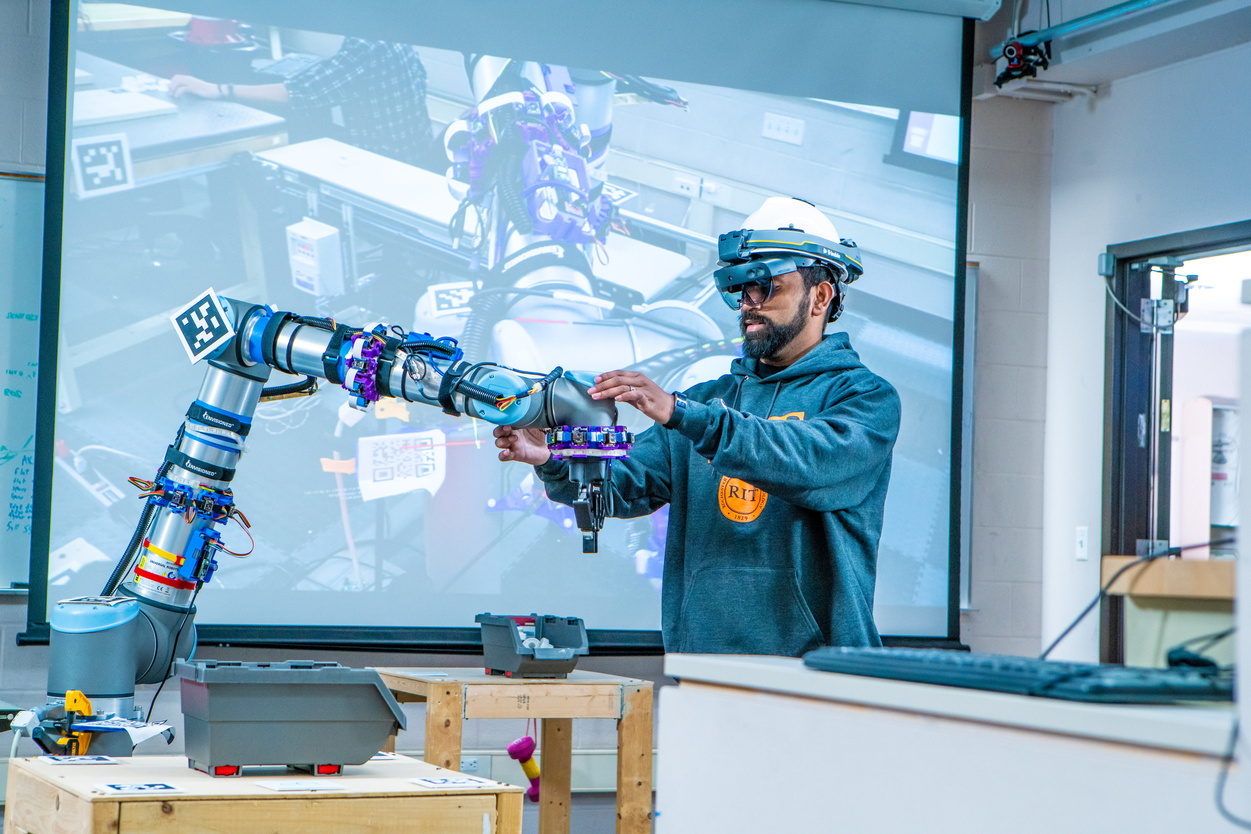 An engineering graduate student tinkering with a robotic arm.