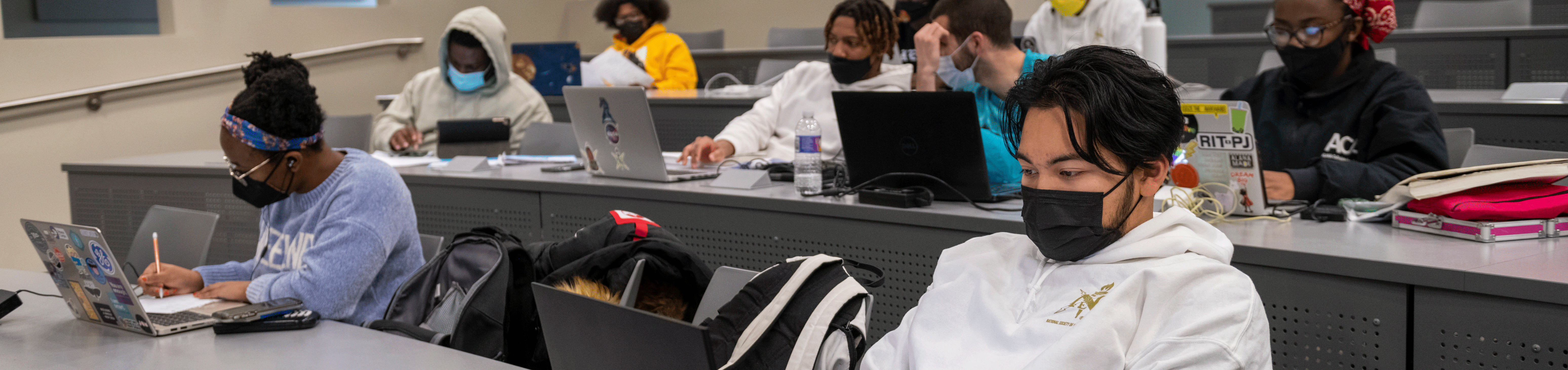 College students studying on laptops in a lecture hall.