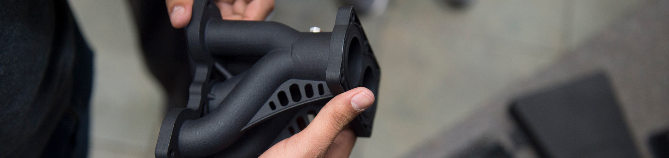 A closeup of a person holding a 3D printed part.
