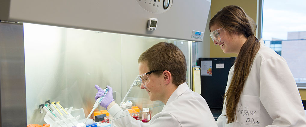 two students working on a chemistry experiment in lab gear