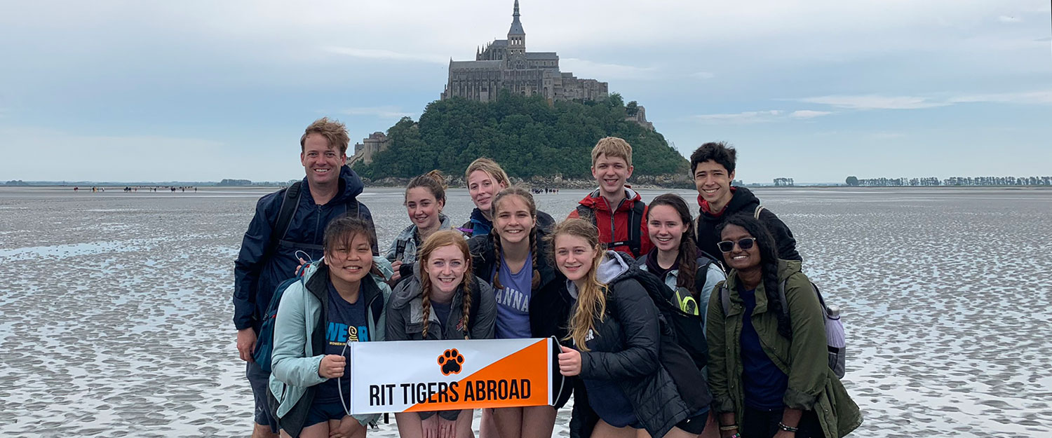 RIT Students with a Faculty member on a beach in front of a castle
