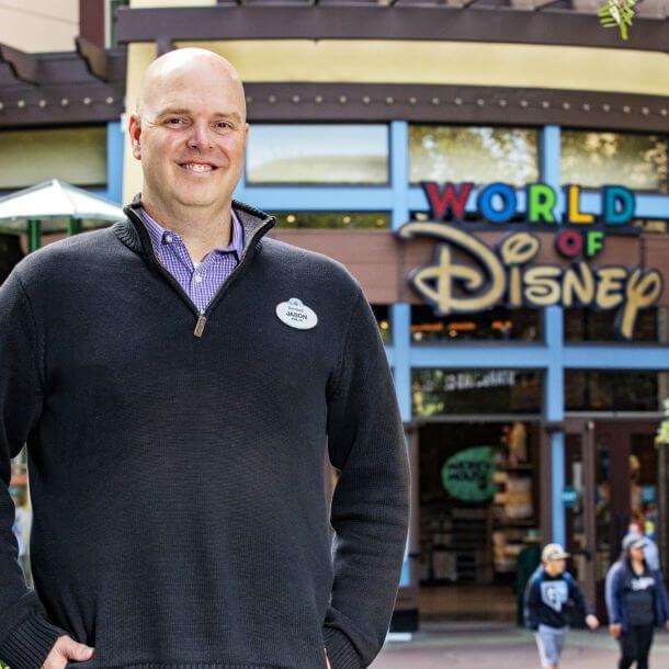Jason Smith smiling in front of a World of Disney sign.