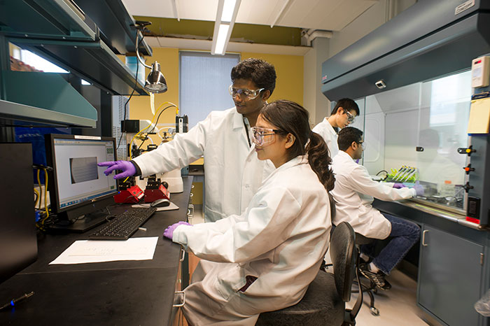 four students working on an experiment in lab gear