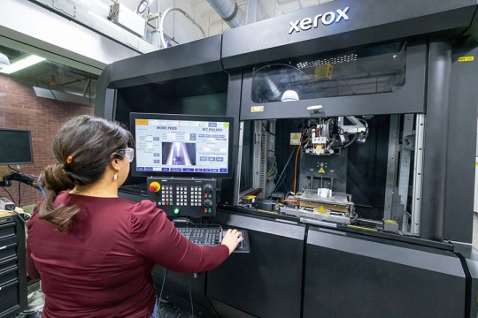A grad student using a metal 3D printer in Brinkman Machine Tools and Manufacturing Lab