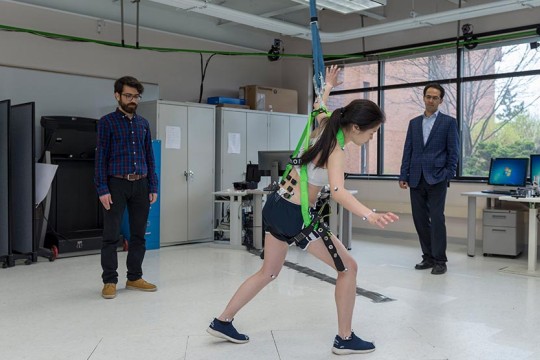 A student wearing and testing motion assessment technology while a student and faculty member observe the movements.
