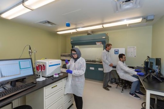 3 people in lab coats working in a lab