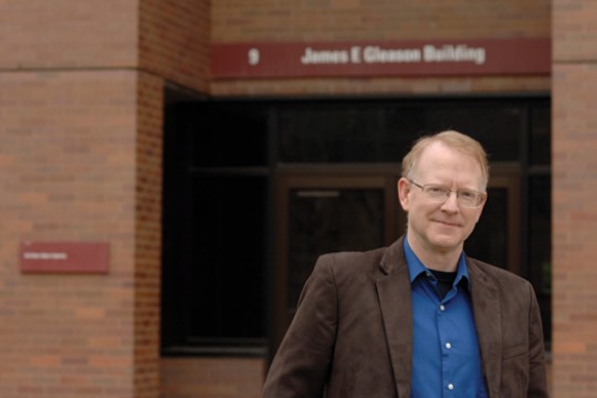 Professor posing for camera in front of class building