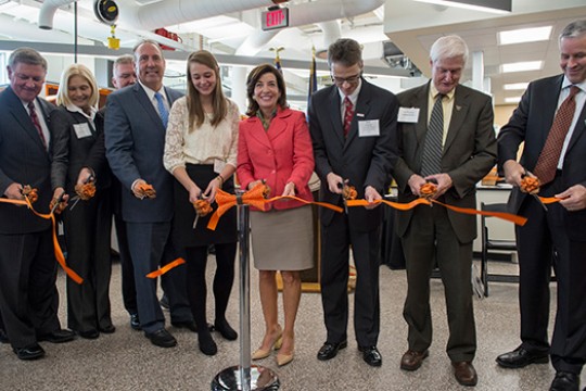 Group of people cutting orange ribbon.