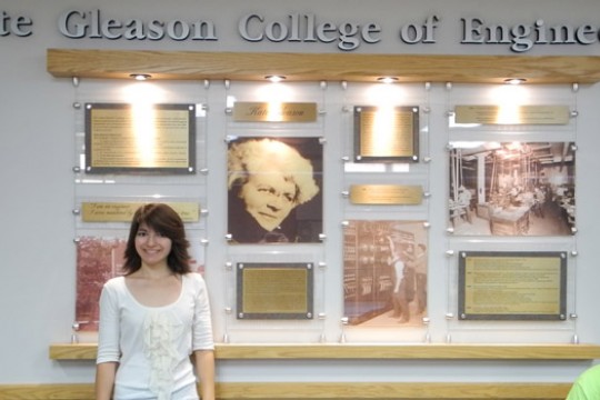 Person posing in front of "The Gleason College of Engineering" sign
