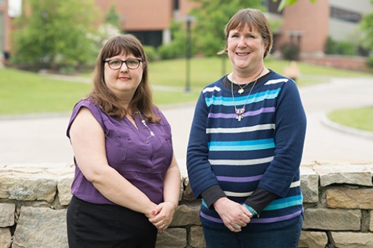 Two people posing next to wall