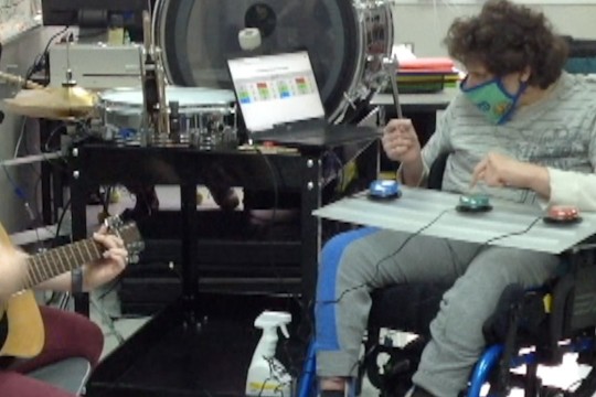 student in a wheelchair using an adaptive drum set.