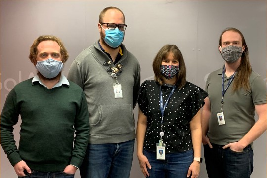 four people wearing face masks posing for a photo.