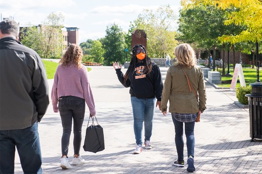 student walking backwards giving a tour of the RIT campus.