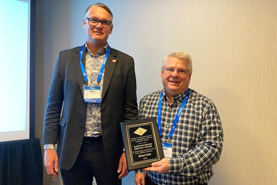 Björn Johansson standing next to Michael Kuhl. Michael is holding an award plaque. 