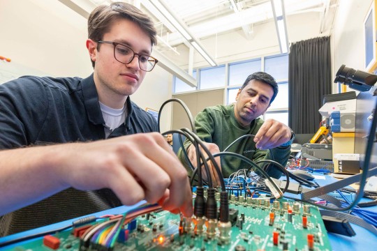 two men work on an integrated circuit in a lab