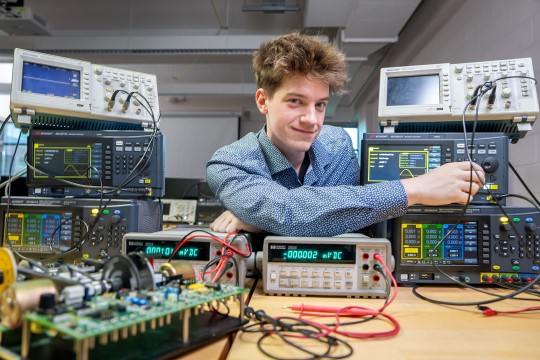 aiden morris sits at a table full of electrical engineering tools