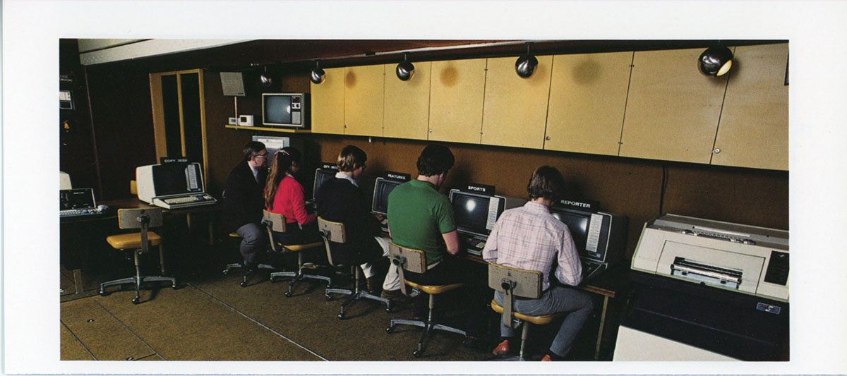 image of five individuals working at old computers next to a printer