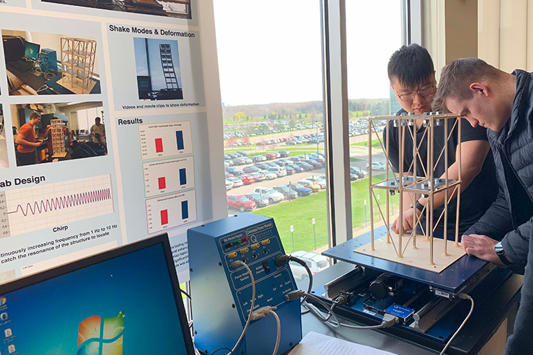 2 people using a testing rig for structural integrity.