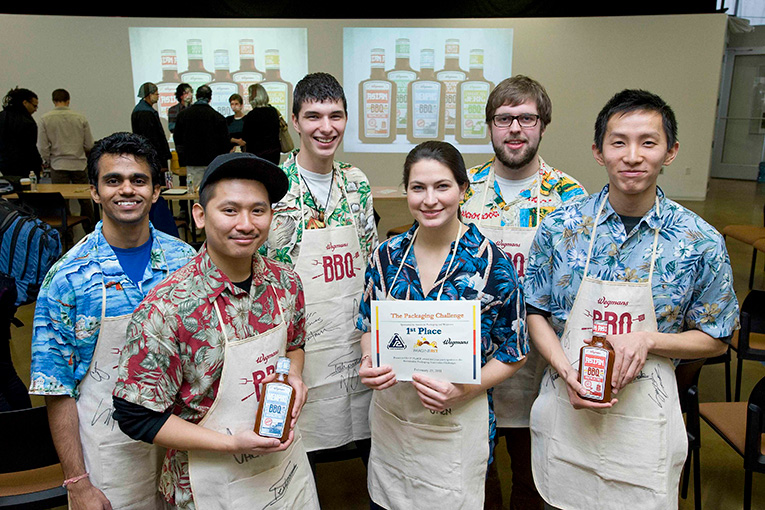 group of students holding an award and several types of packaging.