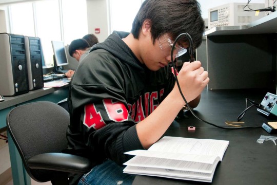 Student soldering at a work station