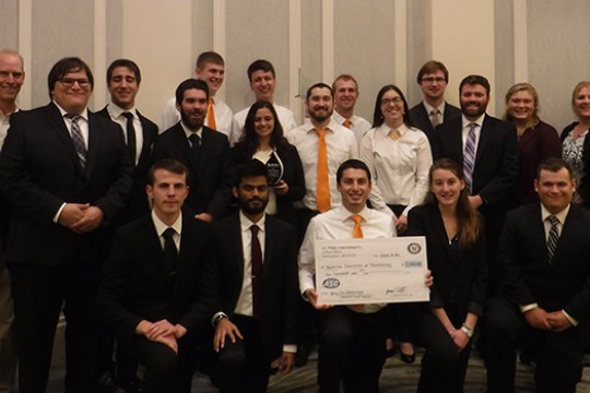 People gathered with award on stage for picture