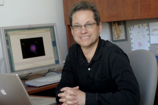 Professor sitting in office next to computers