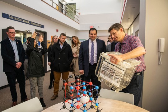 group of people watching a demo with electron models and semiconductor wafers.
